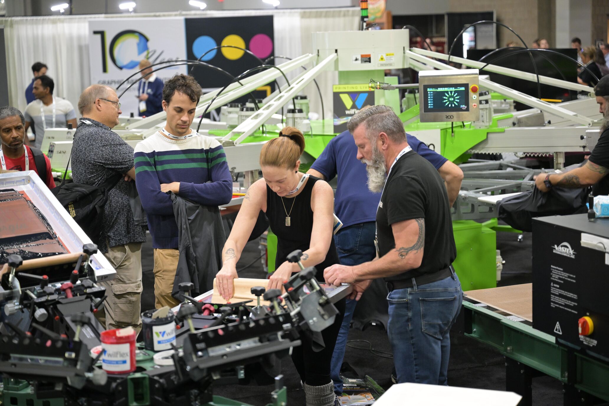 An attendee pulling a squeegee on a manual screen printing press at PRINTING United Expo