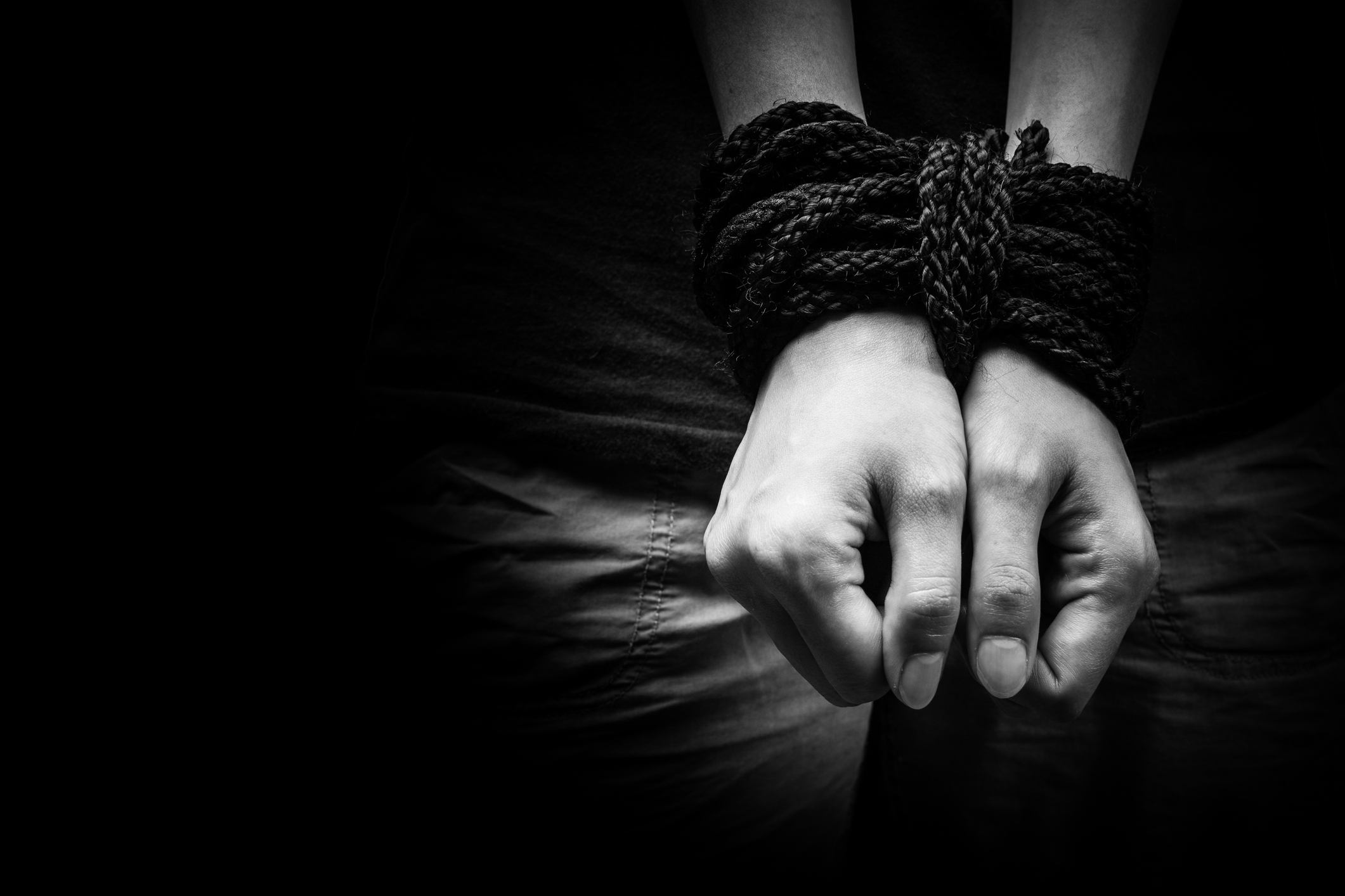 Black and white photo of hands bound by rope.