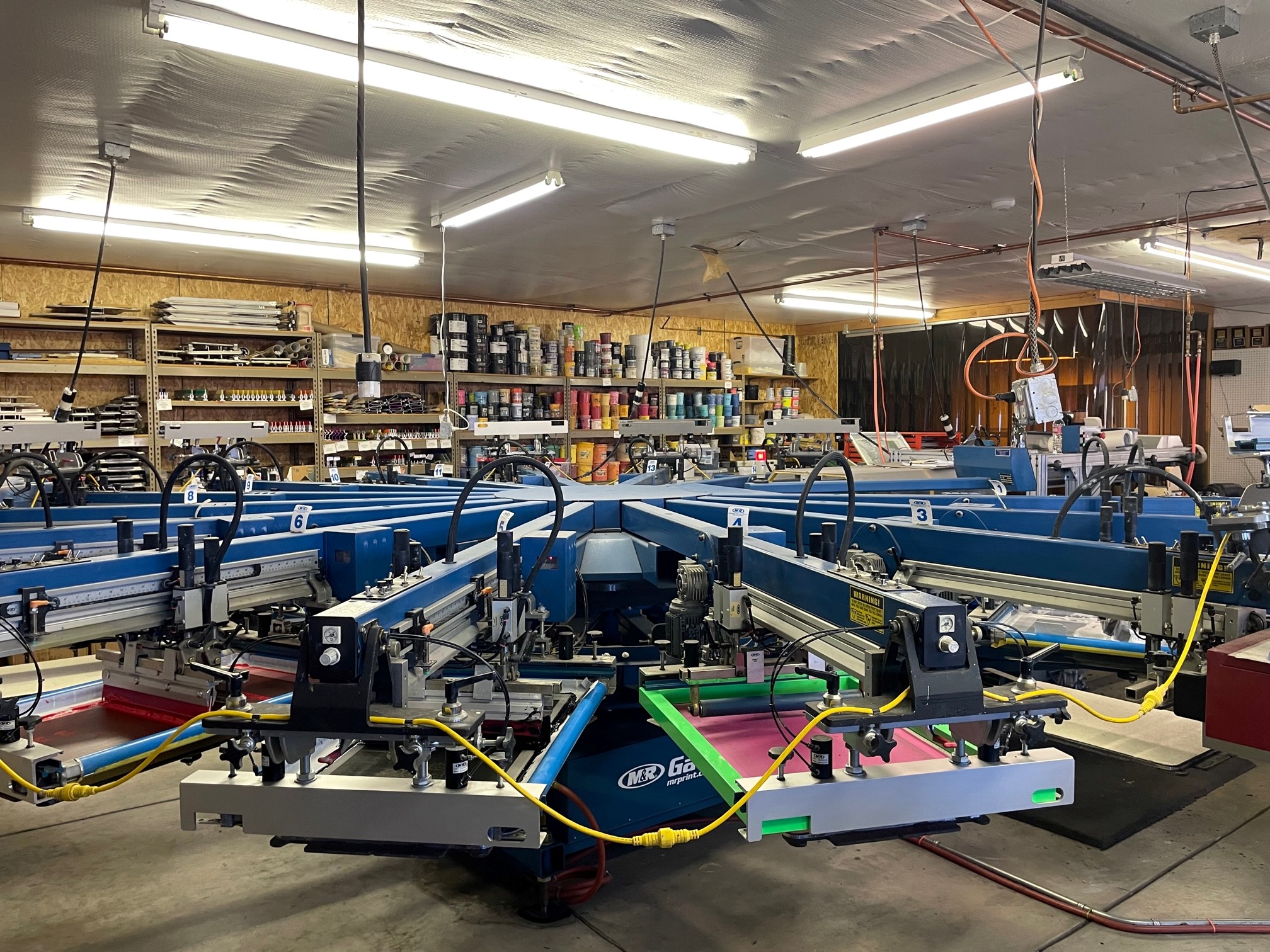 A wide photo of an automatic screen-printing press inside a shop