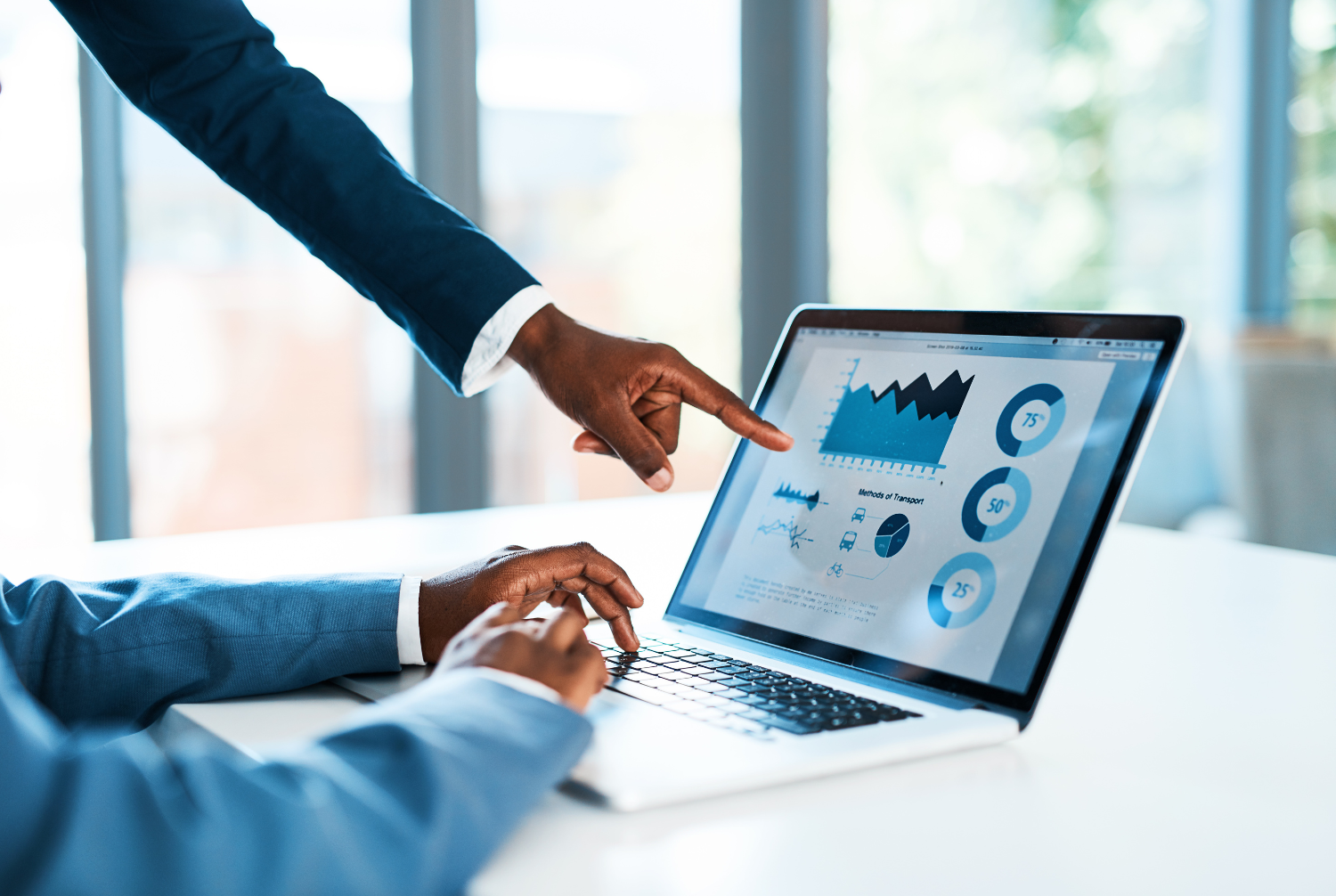 Two people working on a computer that shows financial graphs