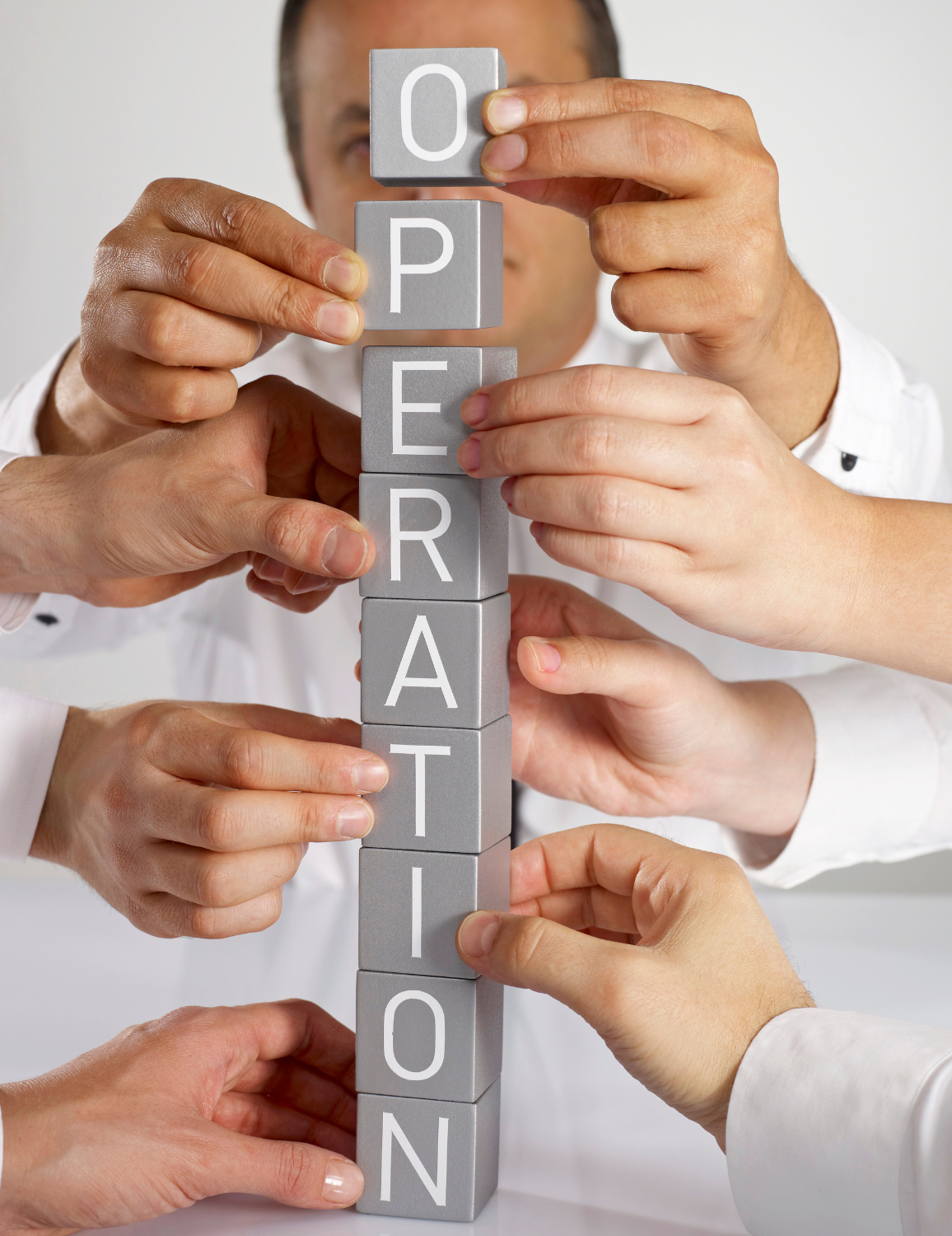 Hands working on building blocks spelling the word "Operation"