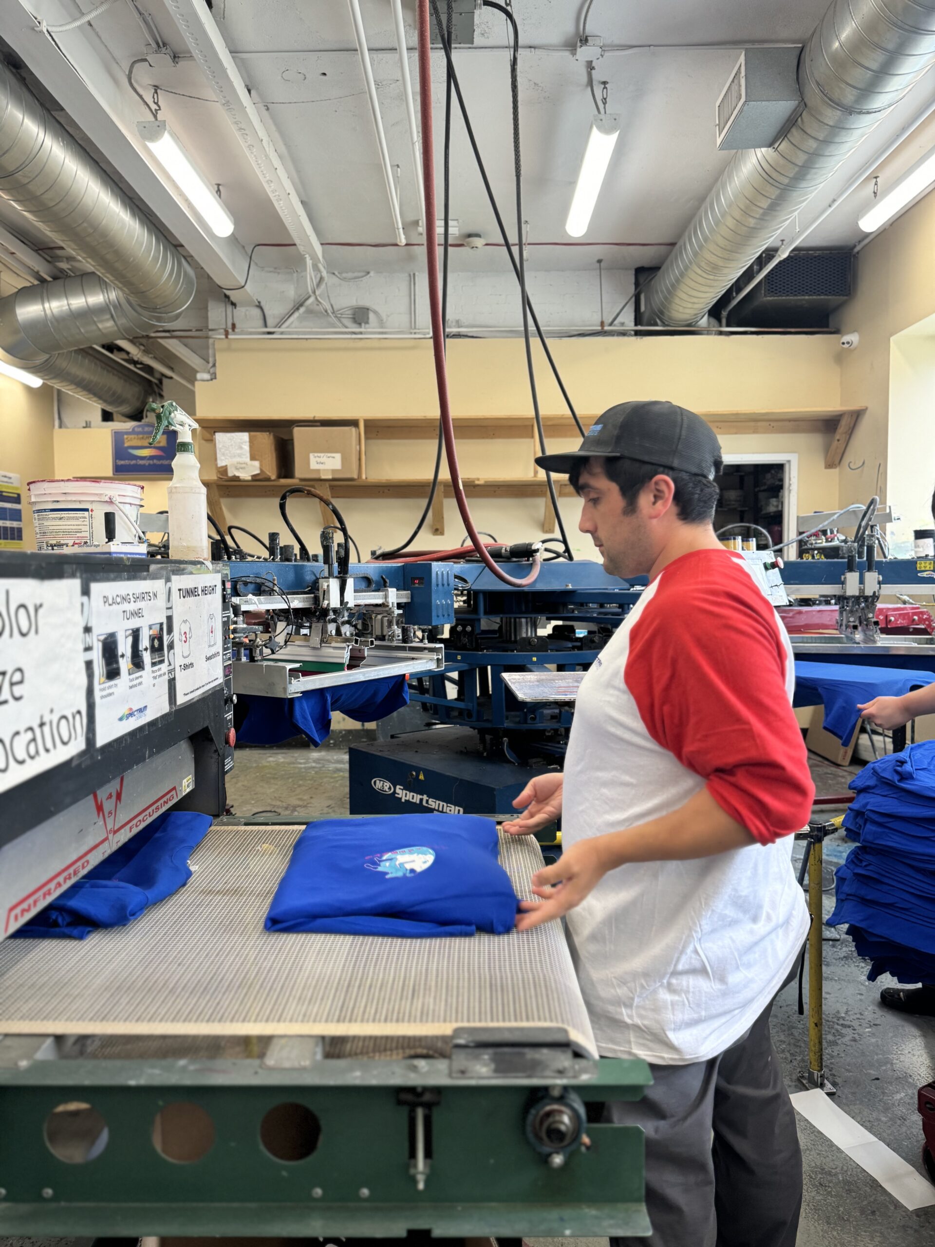 Employee unloading printed shirt of a conveyor dryer