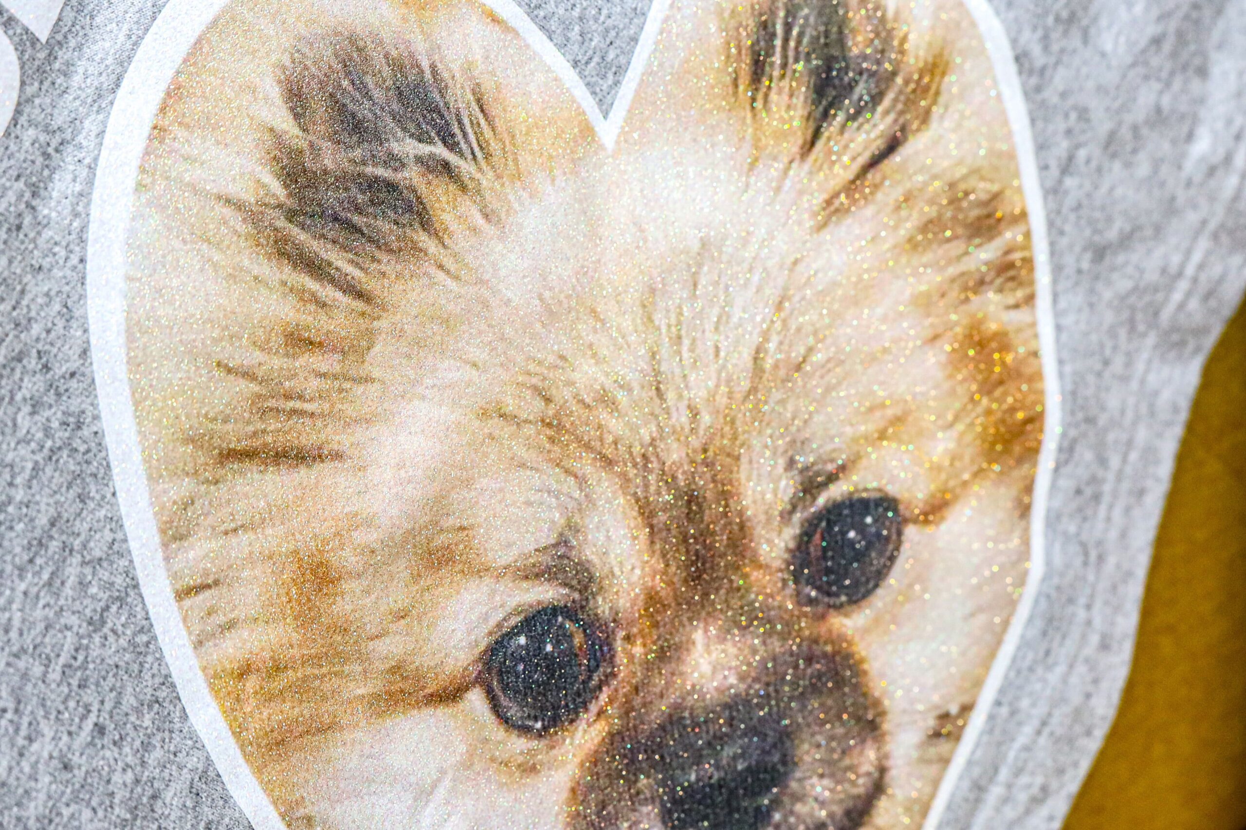 A glitter heat transfer printed with the image of a dog and pressed on a gray shirt