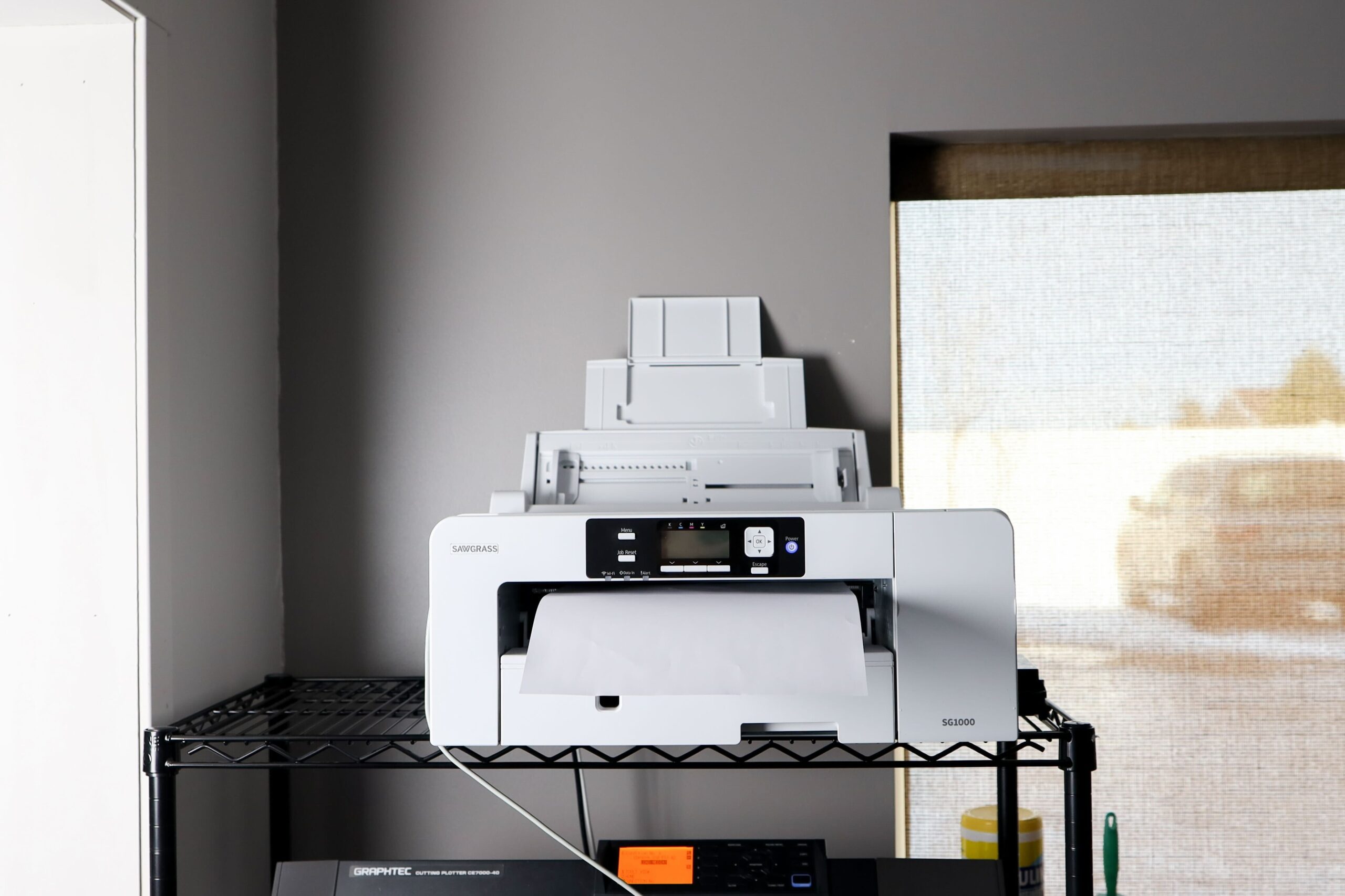 A Sawgrass sublimation printer sitting on a shelf in a home office