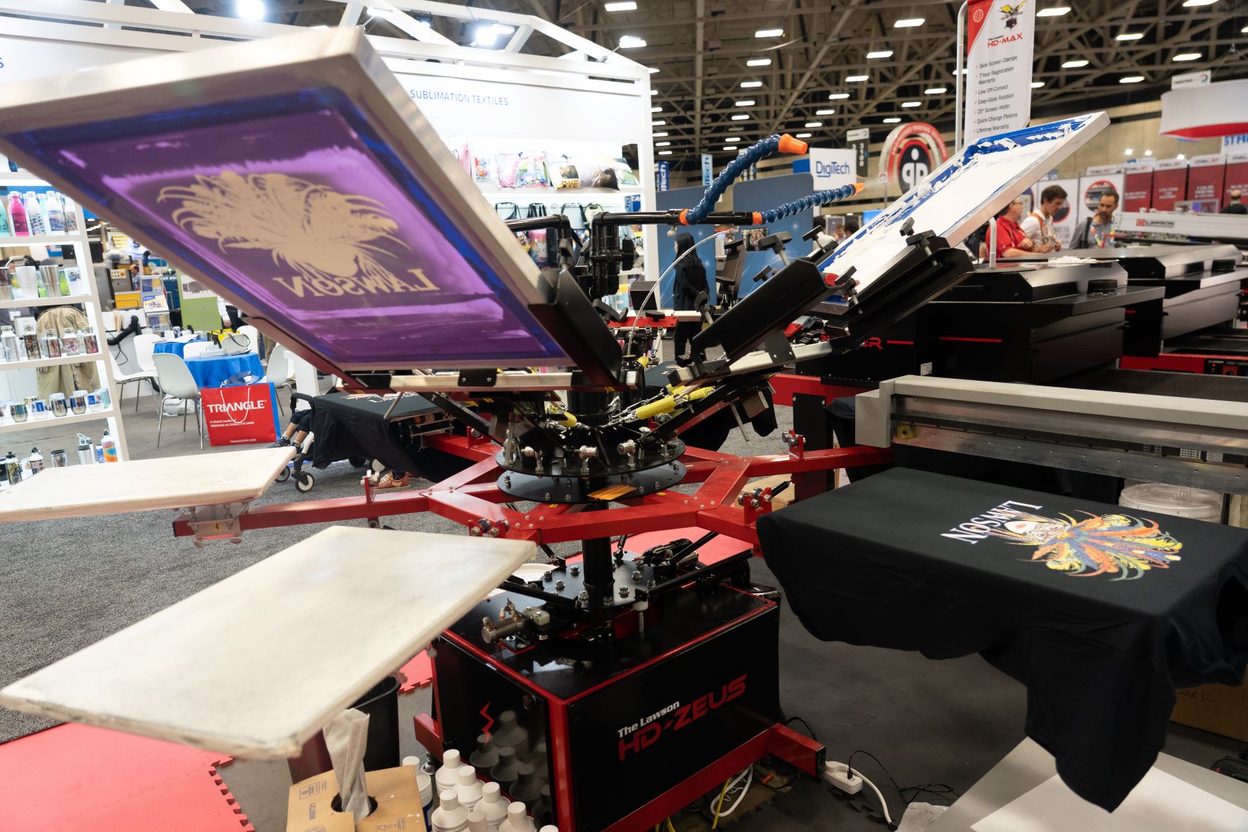 Lawson screen printing press operating on a trade show floor with a Lawson-branded graphic on the screen