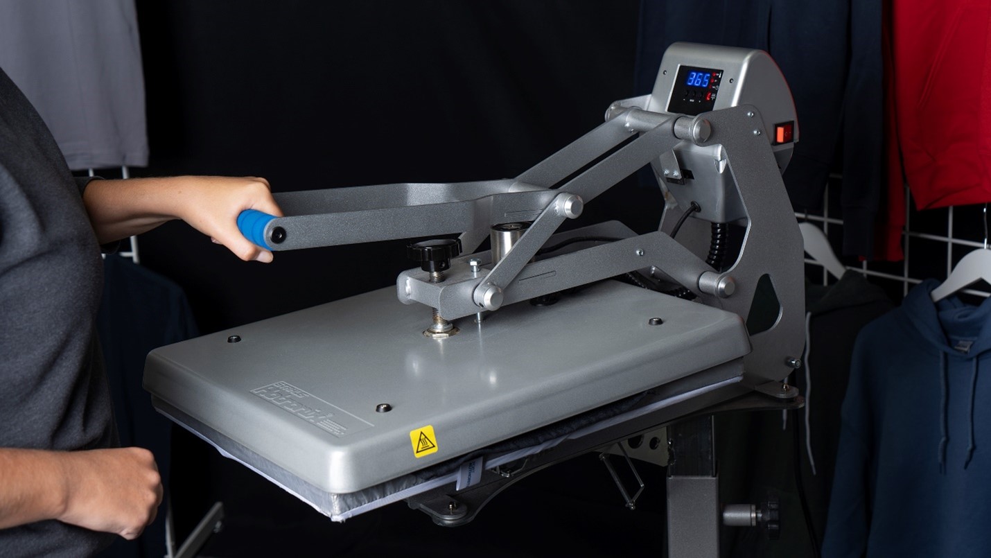 A person pre-pressing a rally towel using a heat press.