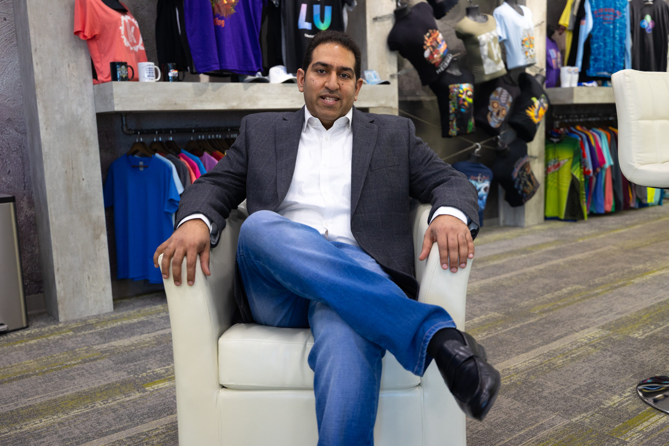 Dinesh Wahi sitting on a white chair in the Shirt Hub showroom