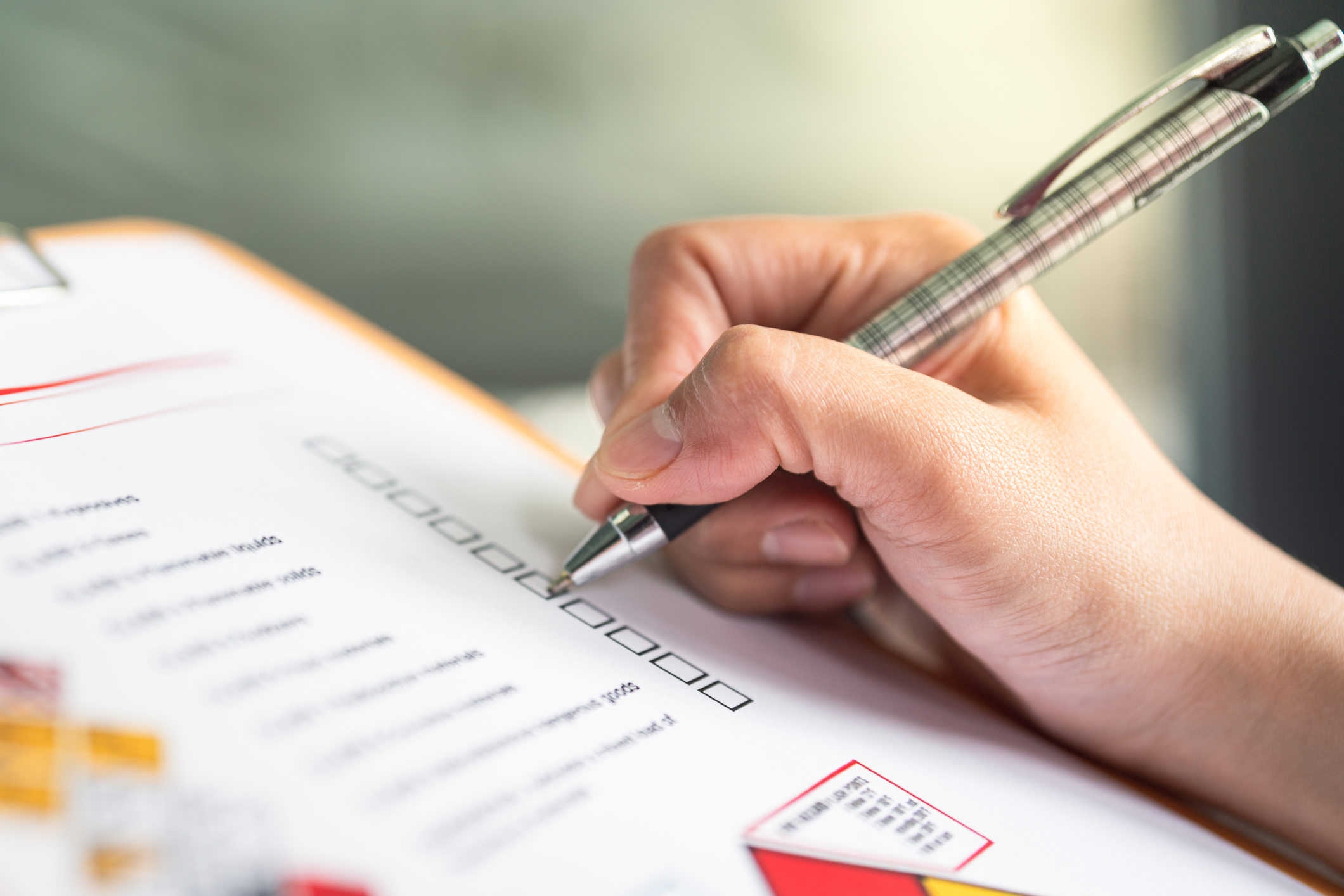 A close-up of a checklist with a hand holding a pen