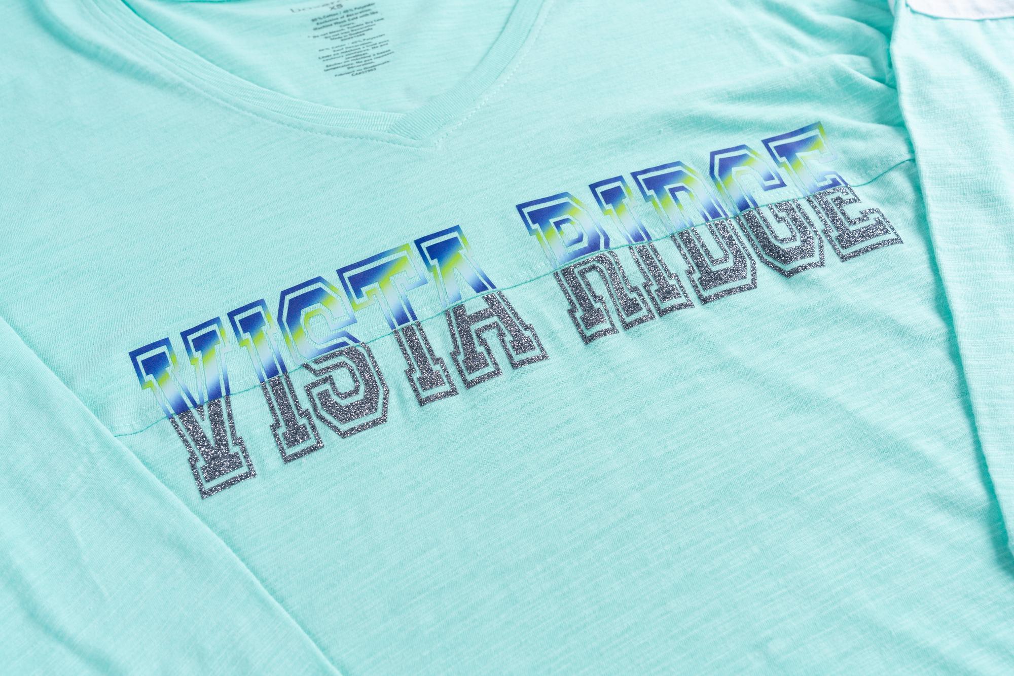 A closeup of a light blue longsleeve featuring a mixed-media design