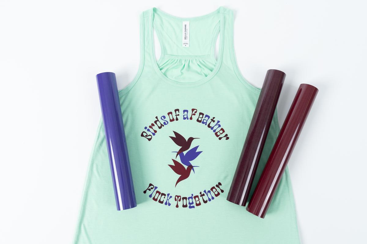 A light green tank top with three rolls ov vinyl laying on top