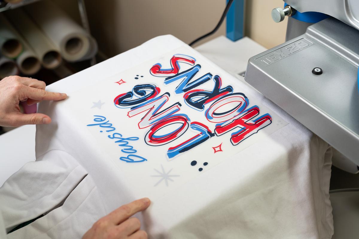 A white hoodie on a heat platen with a red-white-and-blue design