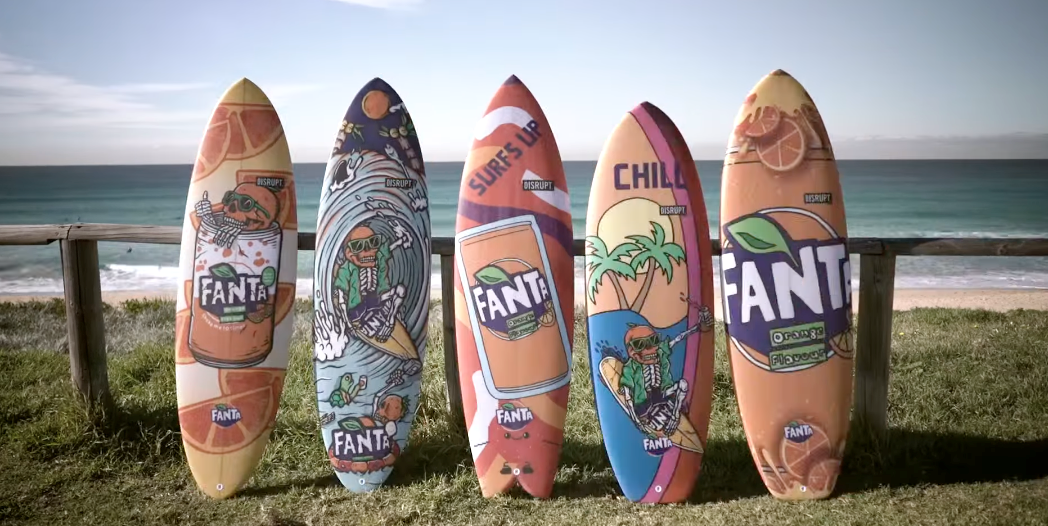 Five surfboards leaning against a stand with Fanta art