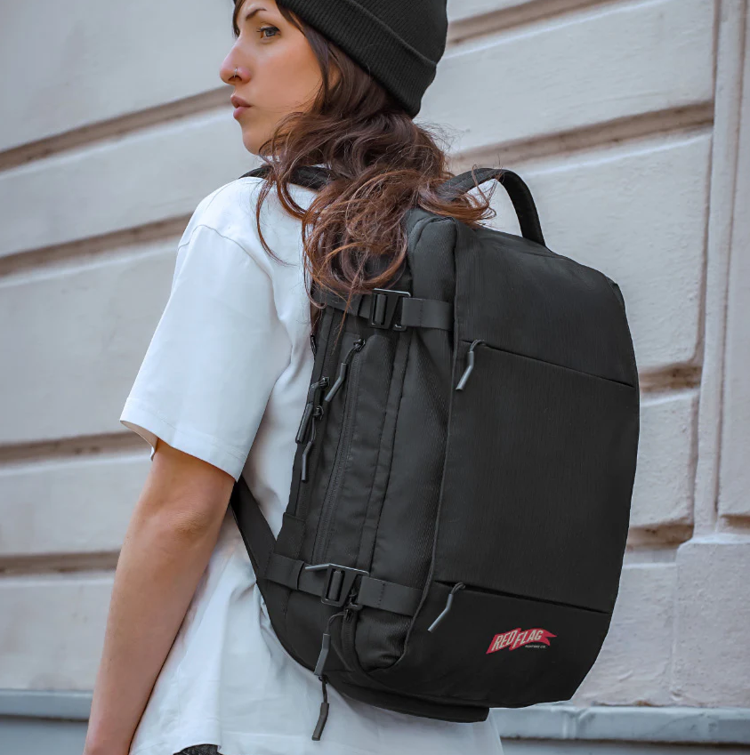A woman wearing a black beanie and white T-shirt wearing a black backpack