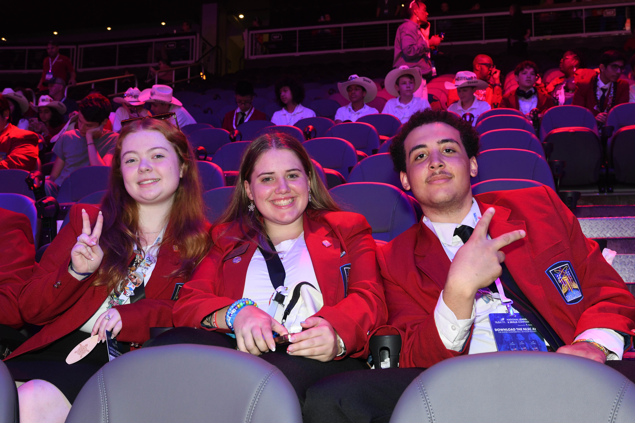 Three students sit in an auditorium at the SkillsUSA nationa competition
