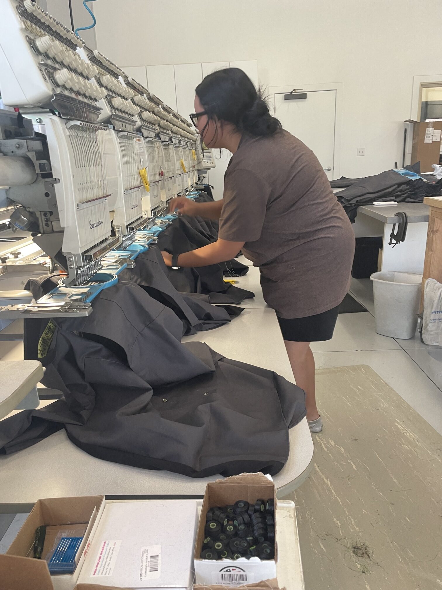 A woman adjusting a shirt on a multi-head embroidery machine