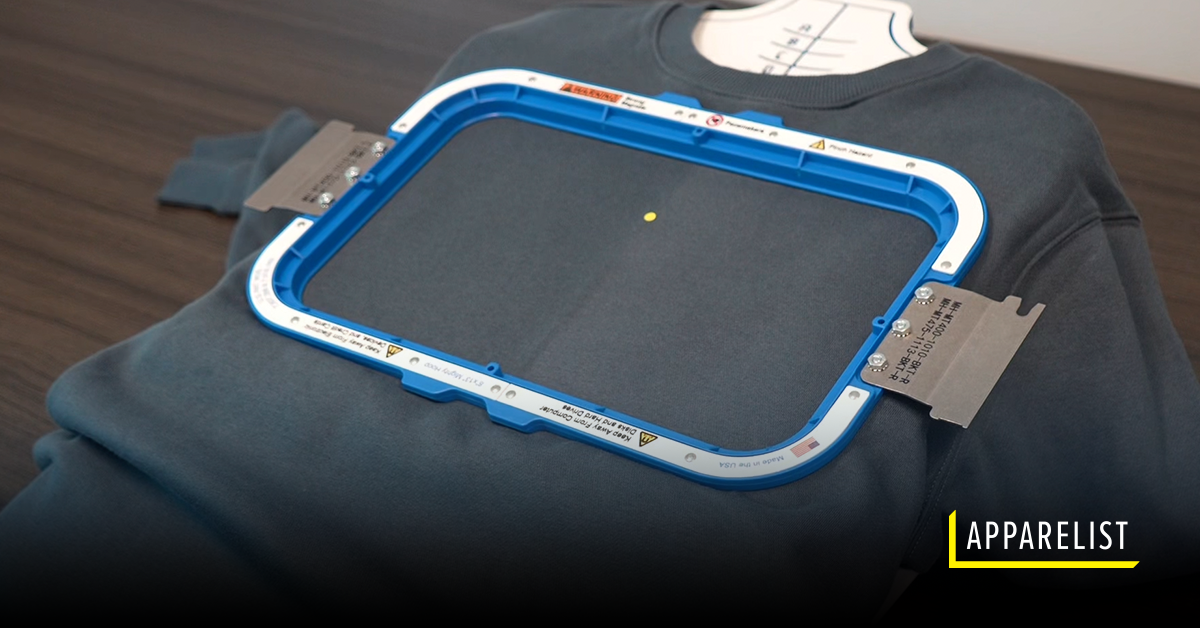 A close-up of a blue sweatshirt loaded onto a Mighty Hoops hooping station.