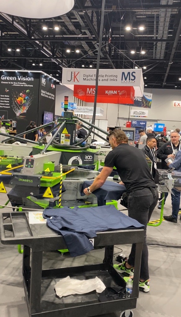 A press operator loading a shirt onto the ROQ Impress machine