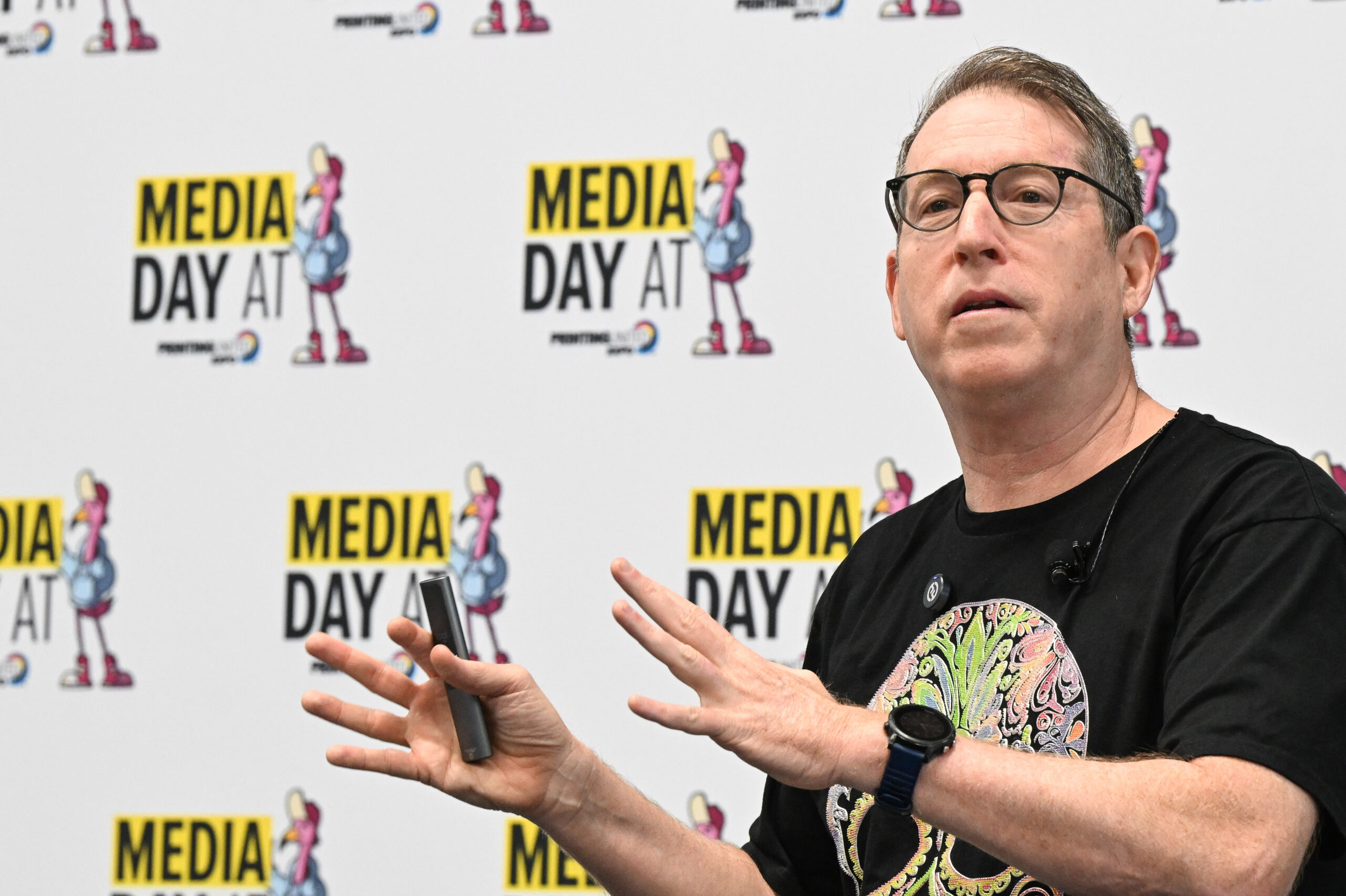 A cloesup of a man talking with step and repeat background