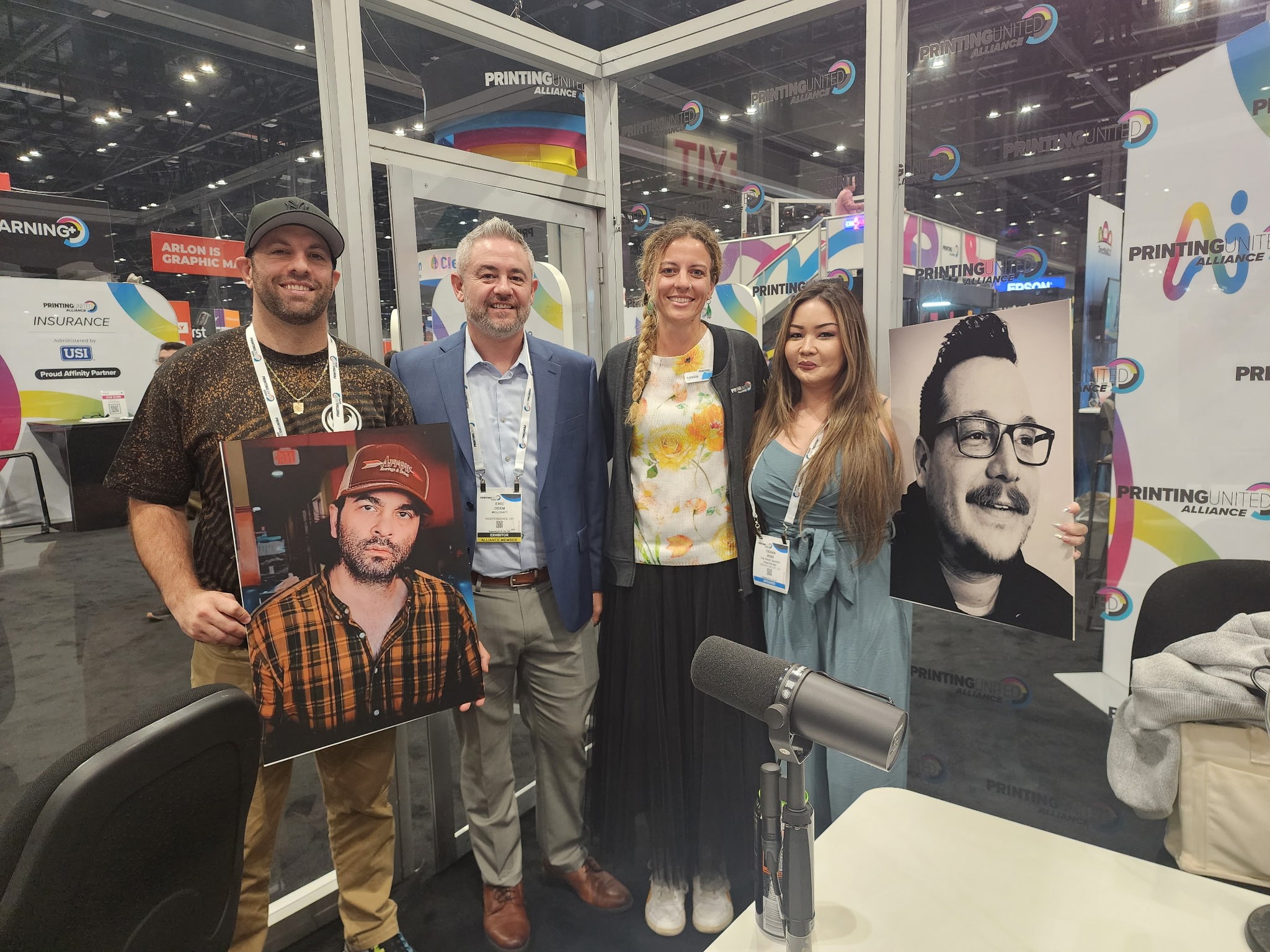 Four people standing with cardboard images of head shots