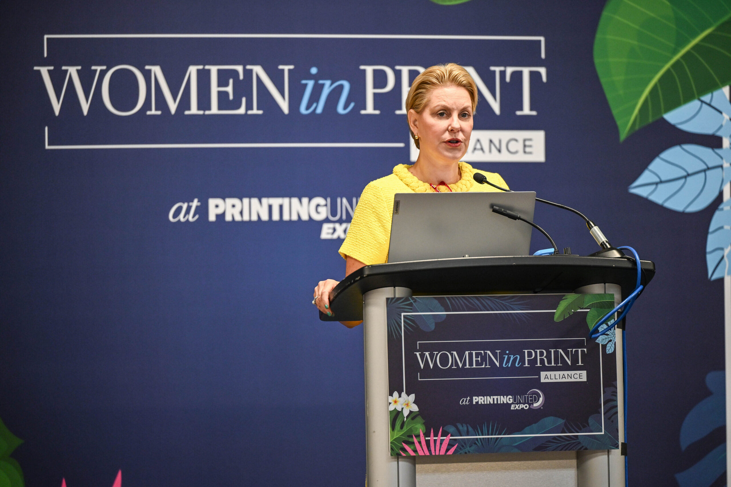 A woman wearing a yellow dress standing at a podium