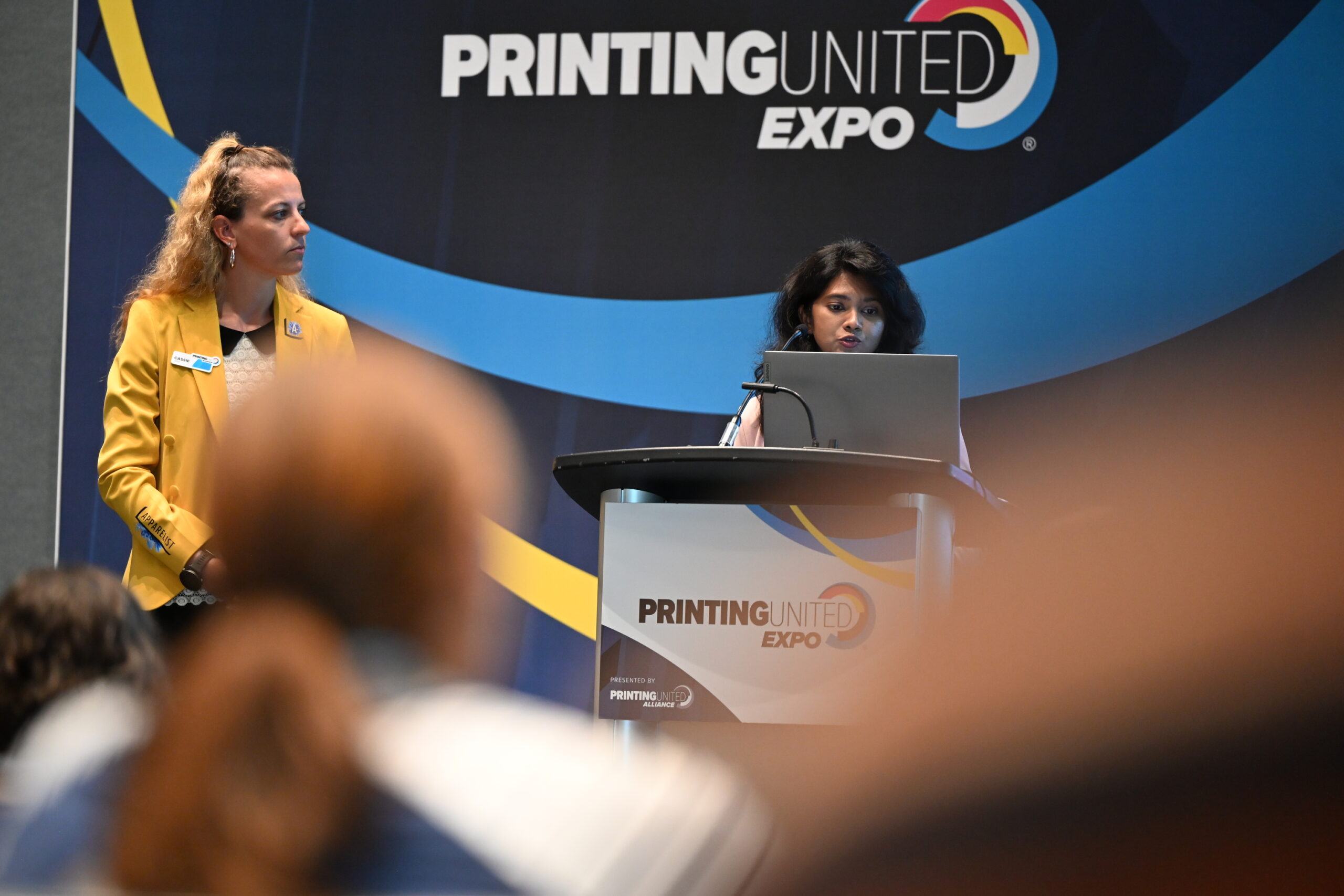two women standing on PRINTING United Expo stage giving a presentation
