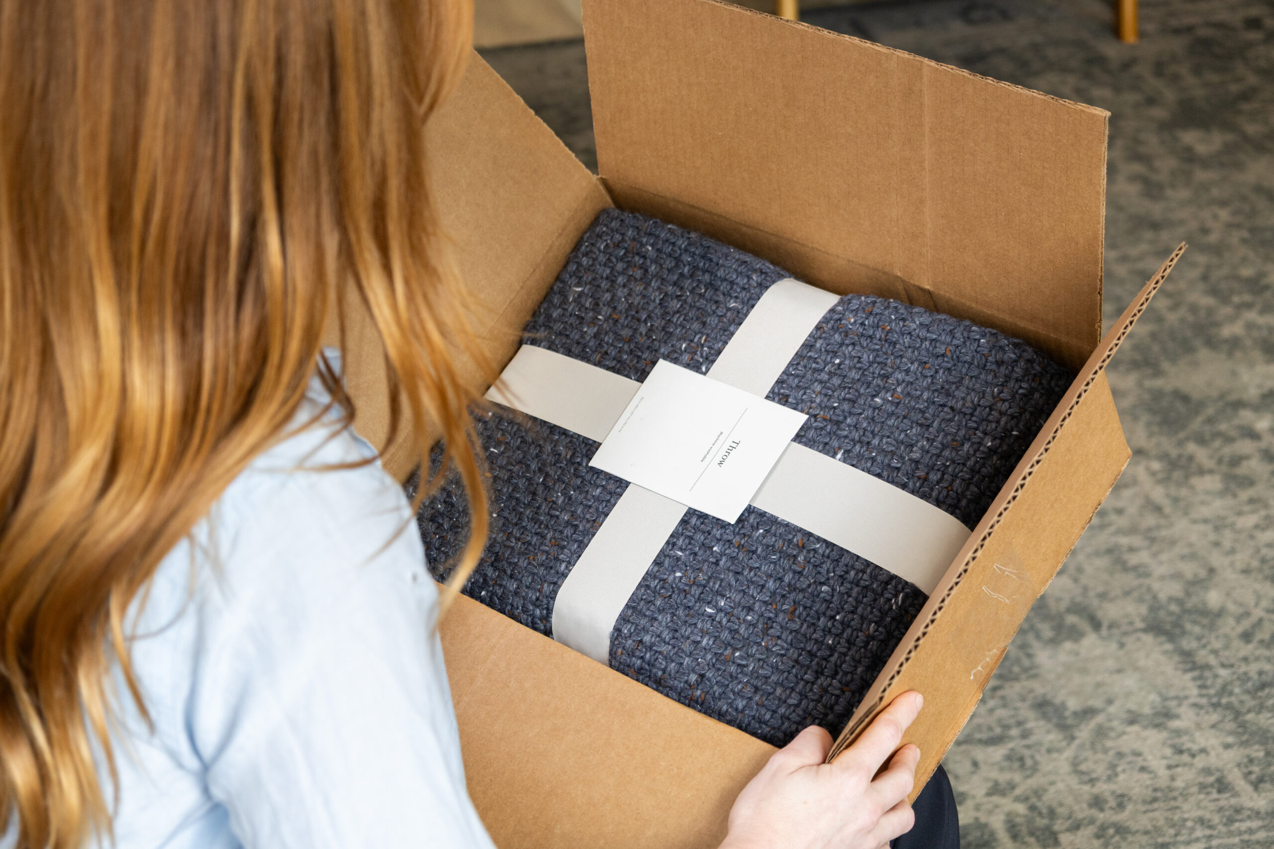 a woman opening a box with a blanket