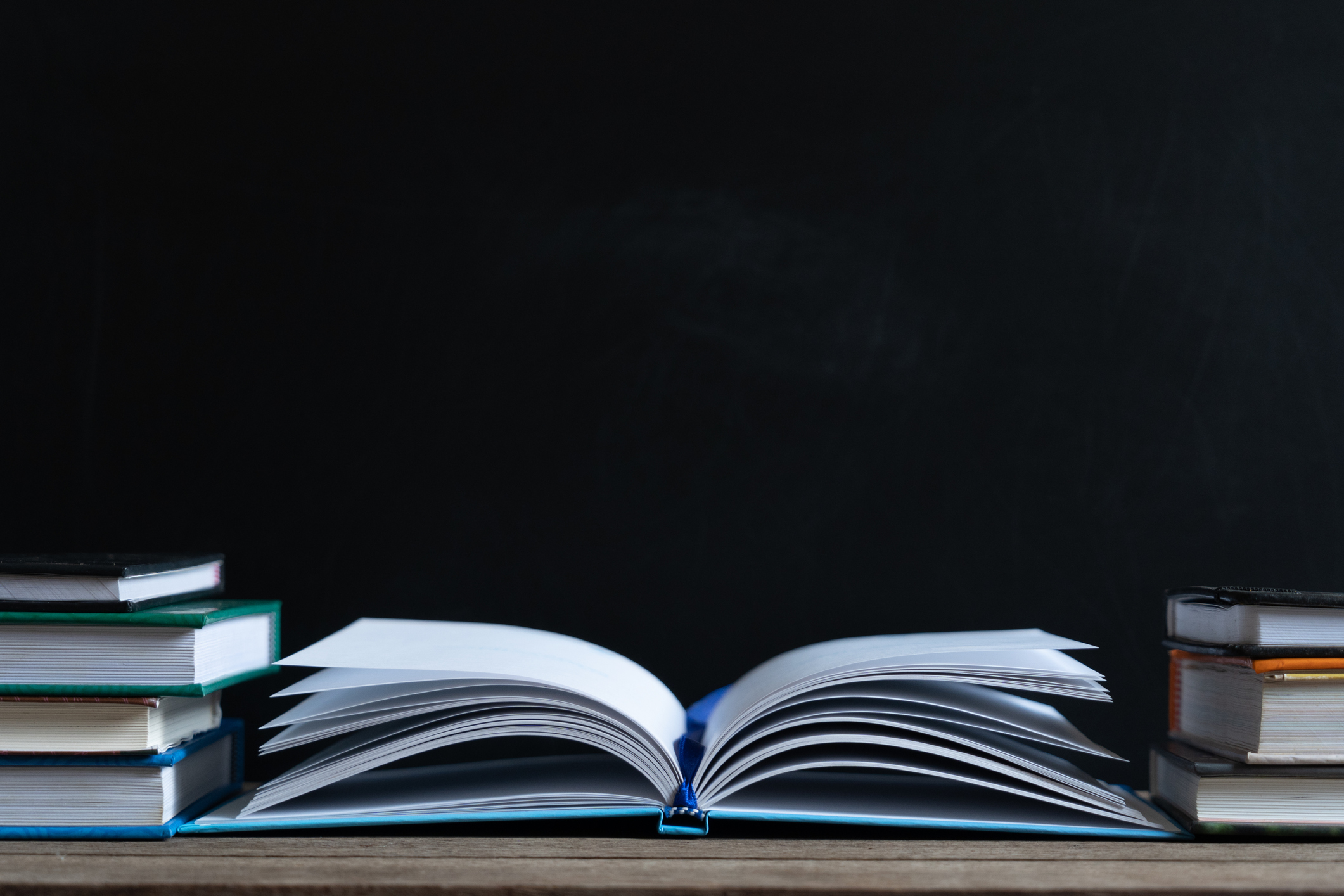 Books and textbook on wooden desk in library selective focus , Piles of books on reading desk in school with copy space for text.World book day and education concept.