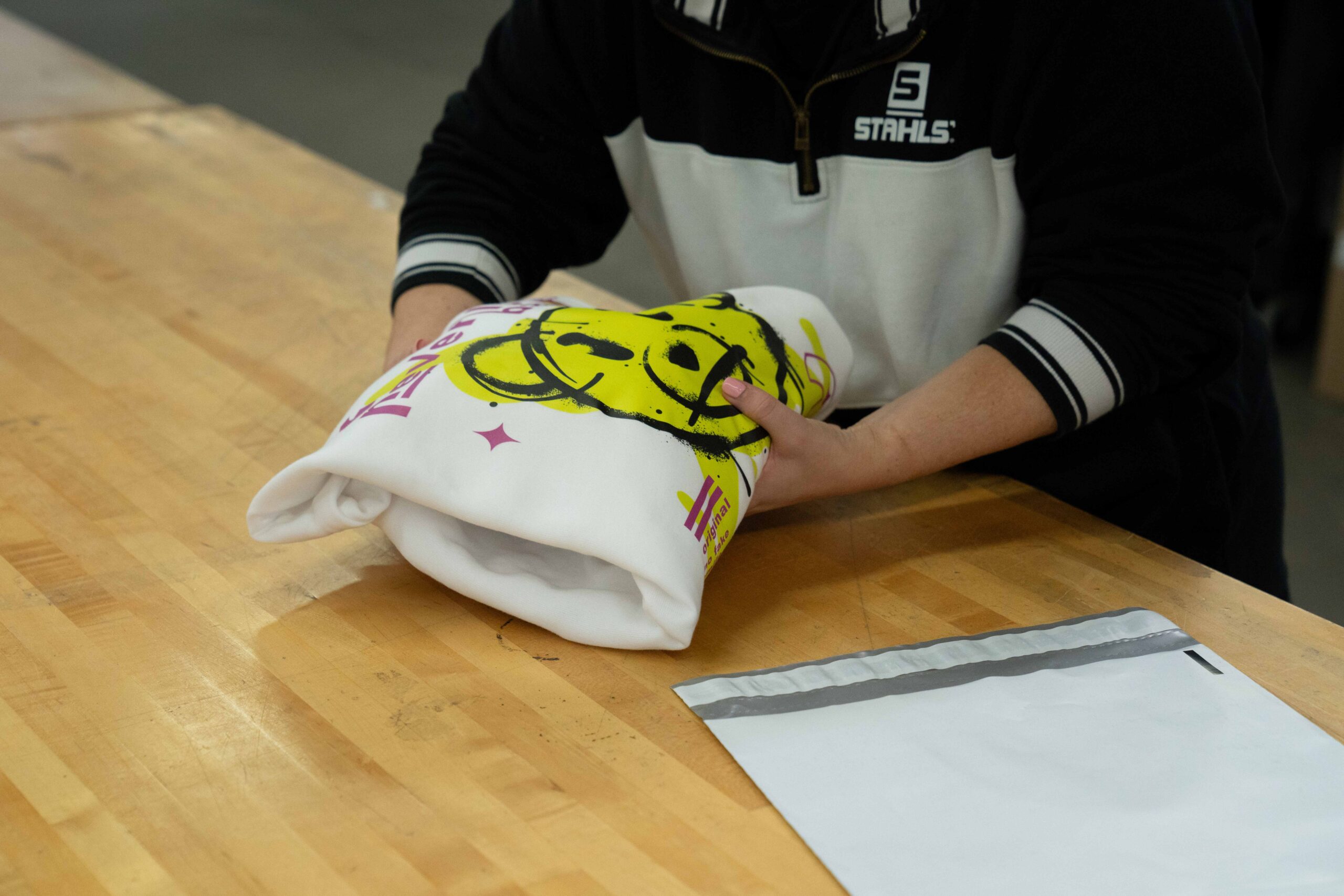 person putting shirt in shipping envelope