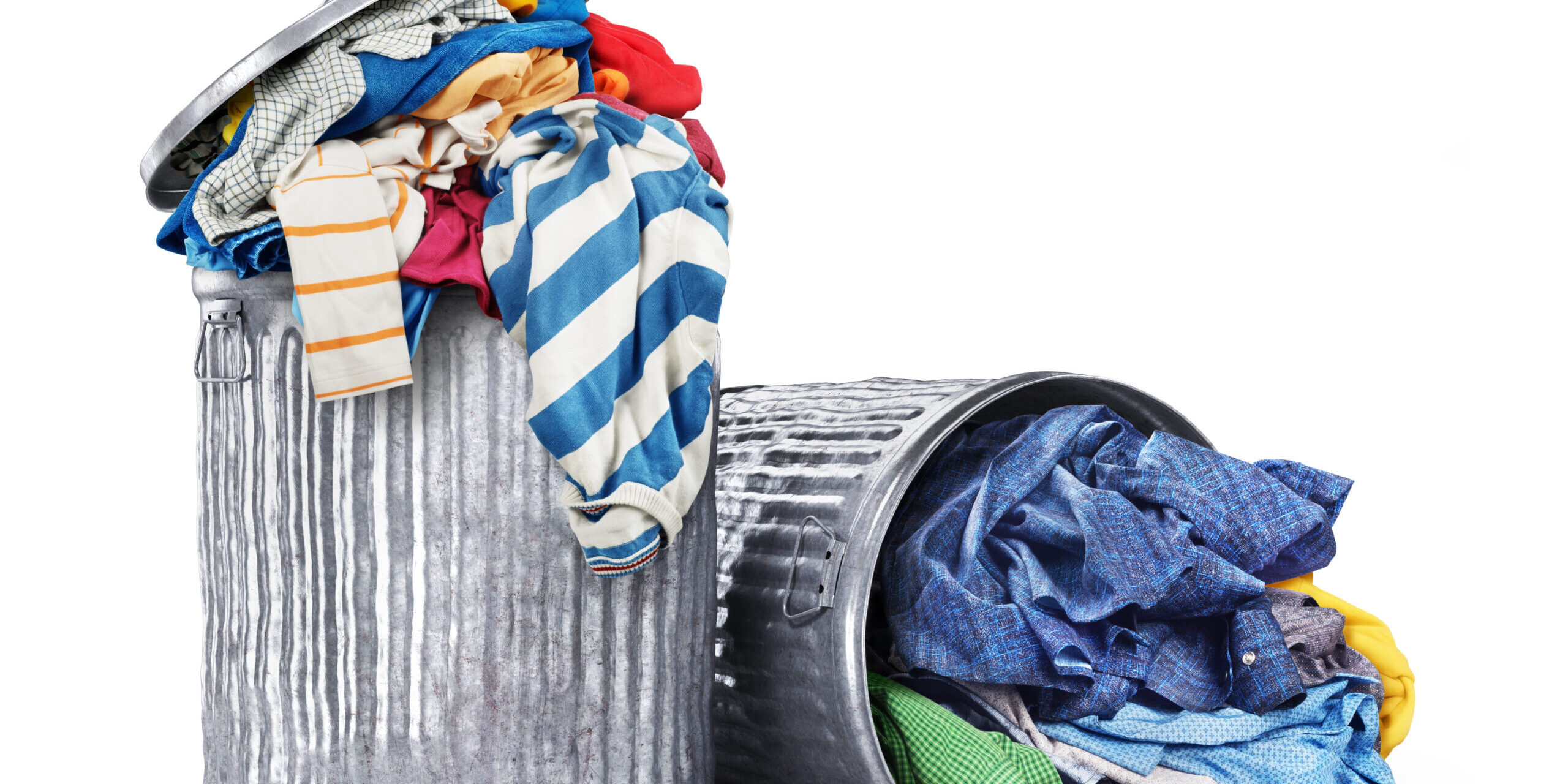 Heaps of clothes in iron dumpsters isolated on a white background. Consumption concept.